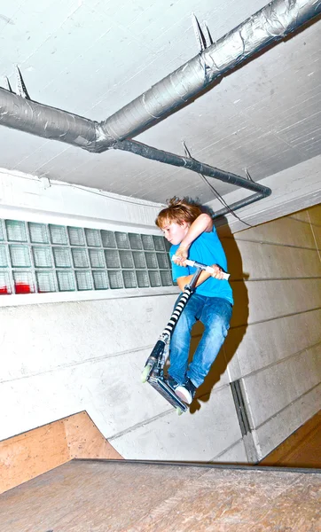 스쿠터를 든 소년 이 스케이트 홀에서 공중으로 날아가고 있어 — 스톡 사진