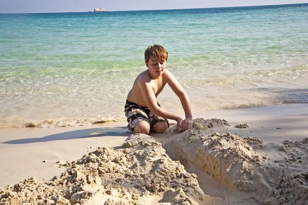 Jungen spielen am Strand mit Sand und bauen Figuren — Stockfoto