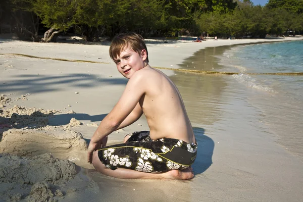Jongens speelt op het strand met zand en het opbouwen van cijfers — Stockfoto