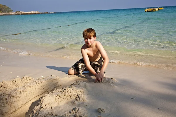 男孩戏剧在沙滩上与沙子和建设数字 — 图库照片
