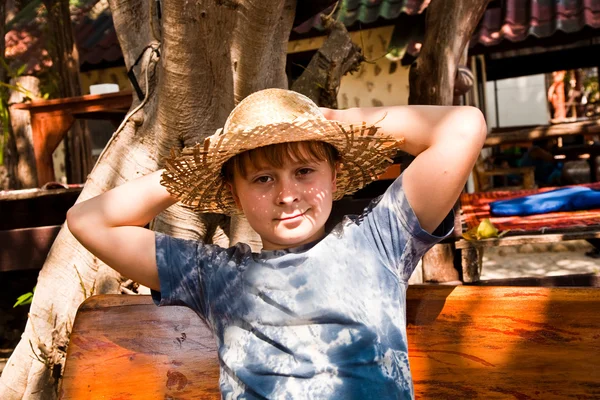 Мальчик расслабляется, улыбается и счастлив и отдыхает на солнце в — стоковое фото