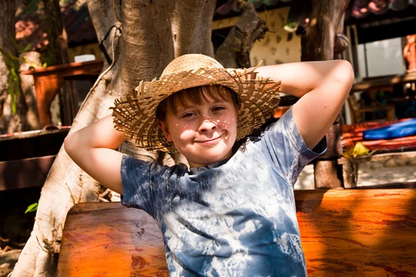 Мальчик расслабляется, улыбается и счастлив и отдыхает на солнце в — стоковое фото