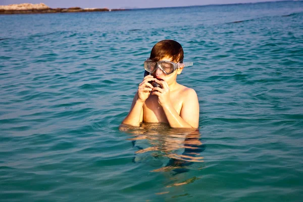 Ung pojke står i det vackra kristallklara havet, njuter av w — Stockfoto