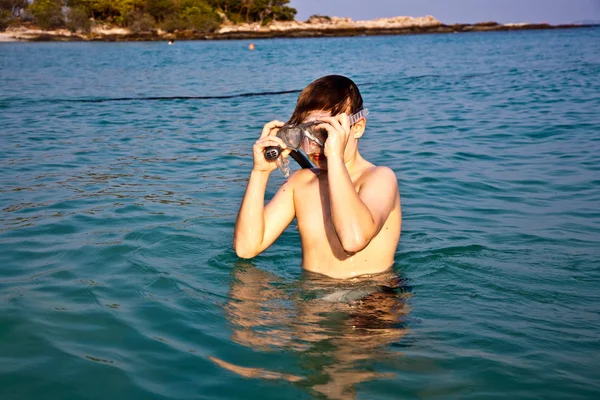 Ung pojke står i det vackra kristallklara havet, njuter av w — Stockfoto