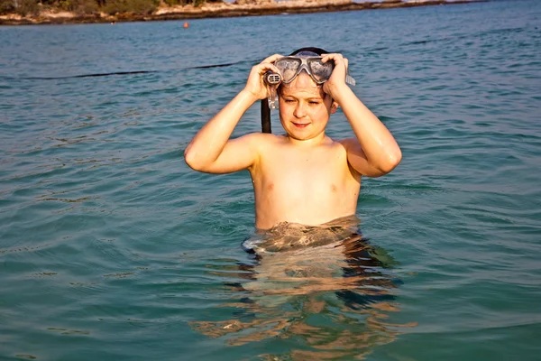 Молодий хлопчик стоїть в прекрасному чистому морі, насолоджуючись w — стокове фото
