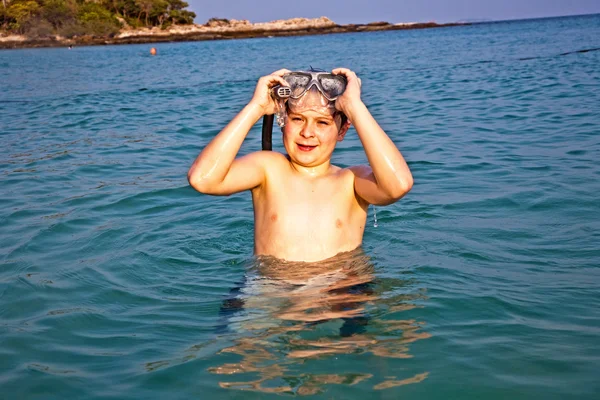 若い男の子は、w を楽しんで、美しい澄んだ海に立っています。 — ストック写真