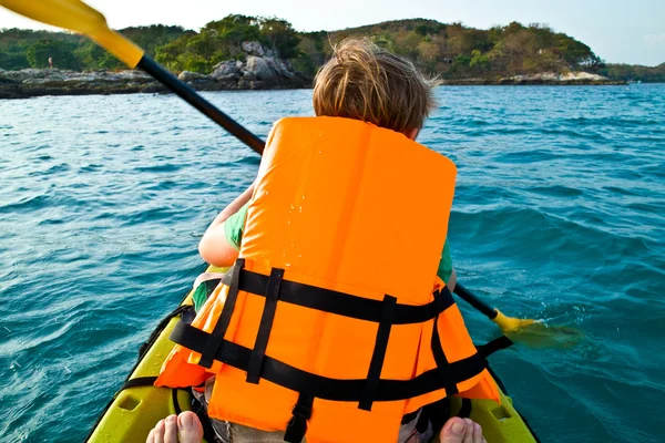 Boy paddling in a canoe at the ocean with safety west — Stock Photo, Image