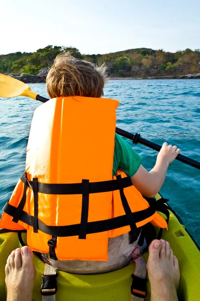 Menino remando em uma canoa no oceano com segurança oeste — Fotografia de Stock