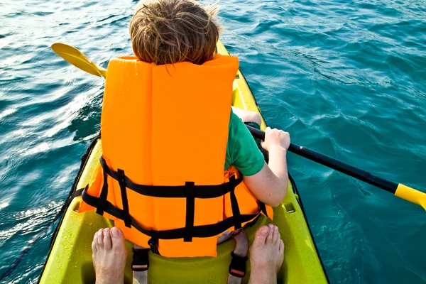 Niño remando en una canoa en el océano con seguridad al oeste — Foto de Stock