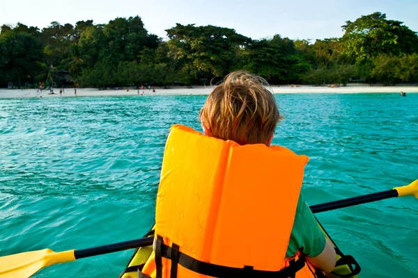 Chico rema en una canoa en el océano con seguridad al oeste —  Fotos de Stock