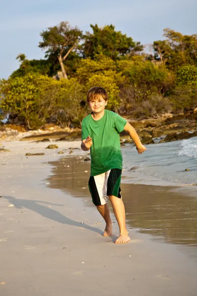 Felice giovane ragazzo sta correndo lungo la bella spiaggia — Foto Stock
