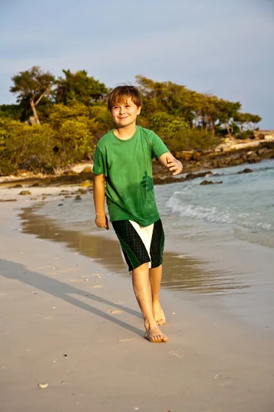 Glad ung pojke kör längs den vackra stranden — Stockfoto