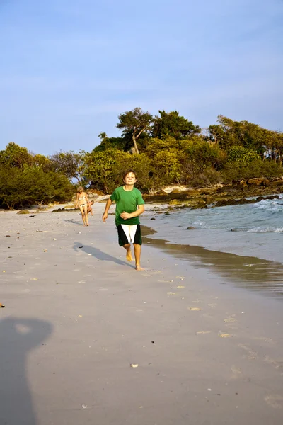 Felice giovane ragazzo sta correndo lungo la bella spiaggia — Foto Stock