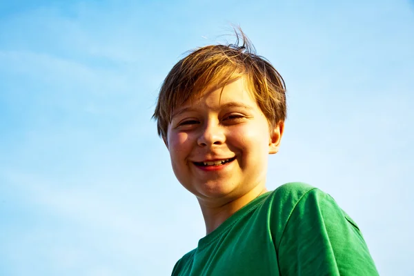 Gelukkig lachend jongen met achtergrond blauwe hemel irissen zijn een — Stockfoto