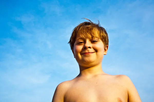 Щасливий усміхнений молодий хлопчик з фоном блакитне небо дає пальці — стокове фото