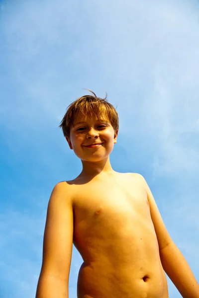 Щасливий усміхнений молодий хлопчик з фоном блакитне небо піднімається його — стокове фото