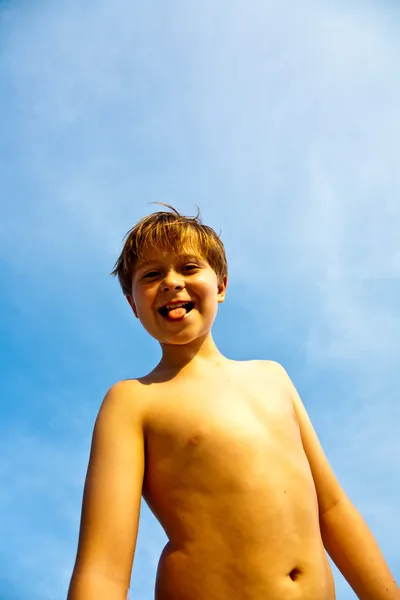 Heureux jeune garçon souriant avec fond bleu ciel iris son a — Photo