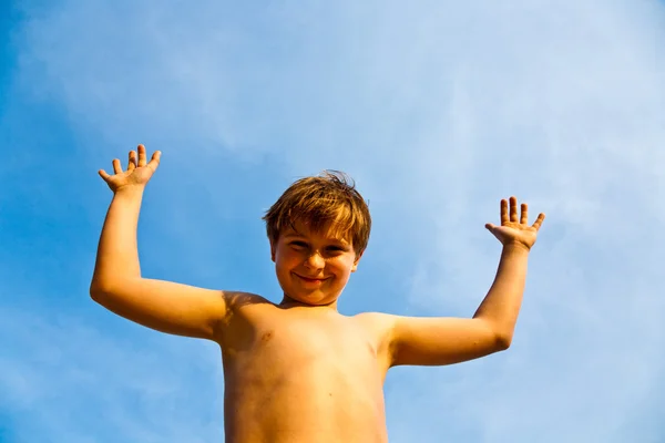 Ευτυχής χαμογελαστοί νεαρό αγόρι με φόντο μπλε ίριδες ουρανό επάνω του ένα — Φωτογραφία Αρχείου