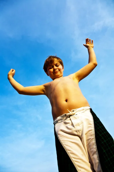 Счастливый улыбчивый мальчик на фоне голубого неба радуется своей — стоковое фото