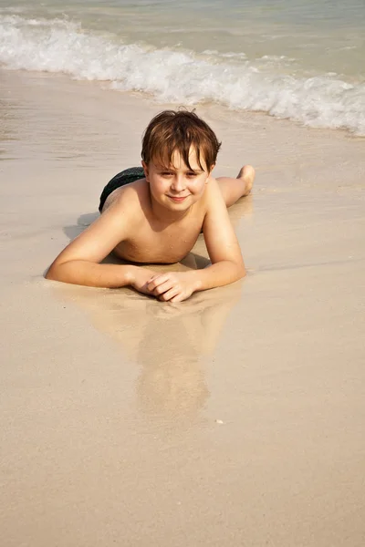 男孩要躺在沙滩上，享受水的暖意 — 图库照片