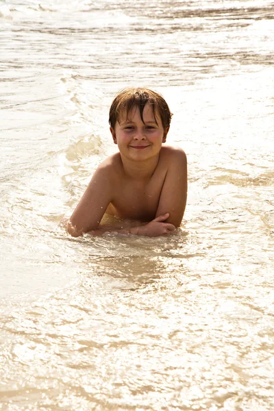 Boy iy lying at the beach and enjoying the warmness of the water — Stock Photo, Image