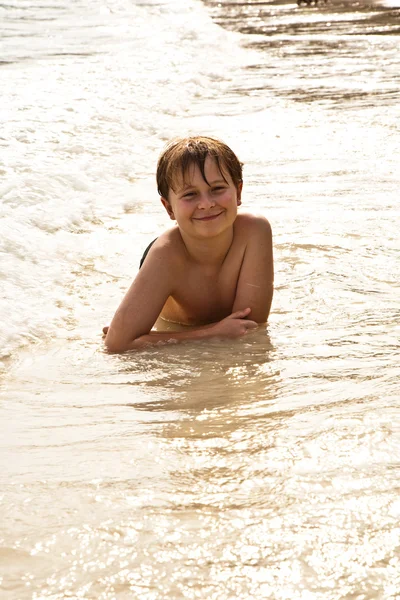 Хлопчик лежить на пляжі і насолоджується теплом води — стокове фото