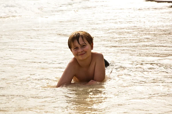 Мальчик лежит на пляже и наслаждается теплом воды — стоковое фото