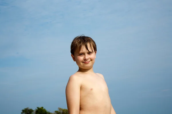 Fröhlicher kleiner Junge mit braunen Haaren und Augen am Strand lächelt — Stockfoto