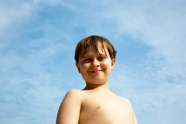Niño feliz con el pelo castaño y los ojos en la playa sonríe —  Fotos de Stock