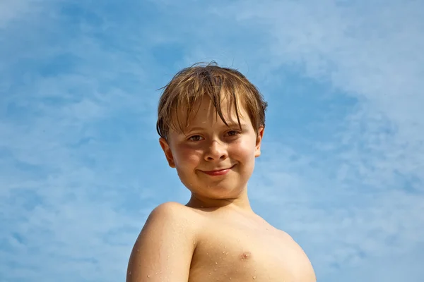 Menino feliz com cabelo castanho e olhos na praia está sorrindo — Fotografia de Stock