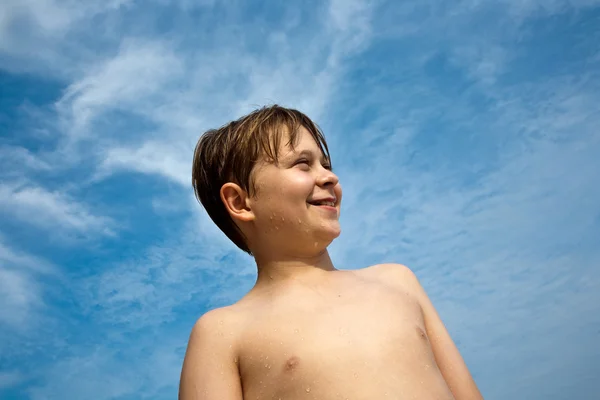 Gelukkige jongen met bruin haar en ogen op het strand is glimlachend — Stockfoto