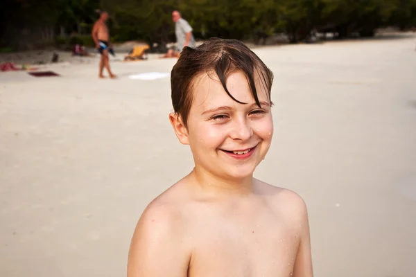 Молодой счастливый мальчик с каштановыми мокрыми волосами улыбается и наслаждается — стоковое фото