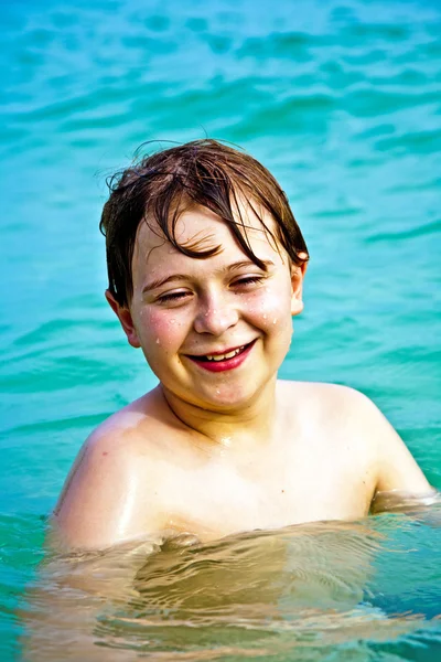 Jovem menino feliz com cabelo castanho gosta de brincar na bela — Fotografia de Stock