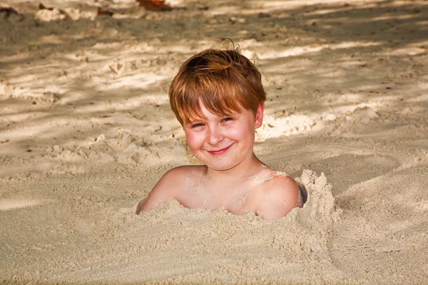 Šťastný chlapec, na které se vztahuje jemný písek na pláži — Stock fotografie