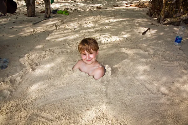 Happy young boy covered by fine sand at the beach — Stock Photo, Image