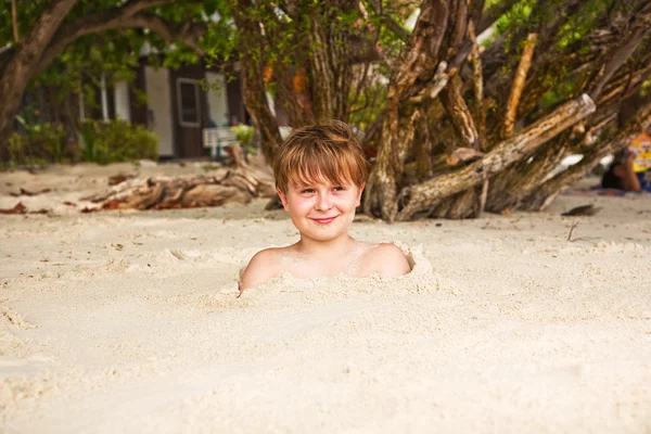 Felice giovane ragazzo coperto di sabbia fine in spiaggia — Foto Stock