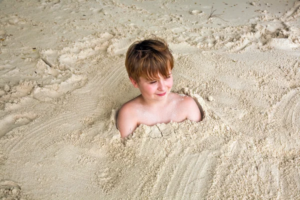 Glücklicher kleiner Junge am Strand mit feinem Sand bedeckt — Stockfoto