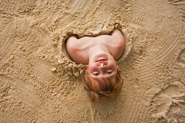 Gelukkige jongen vallende fijn zand op het strand — Stockfoto