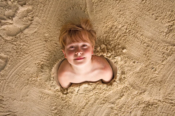 Glücklicher kleiner Junge am Strand mit feinem Sand bedeckt — Stockfoto