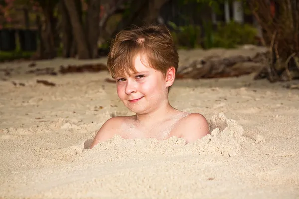 Glücklicher kleiner Junge am Strand mit feinem Sand bedeckt — Stockfoto