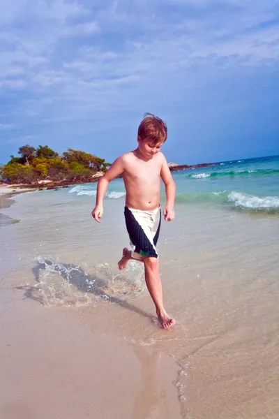 Молодой милый мальчик идет вдоль прекрасного пляжа — стоковое фото