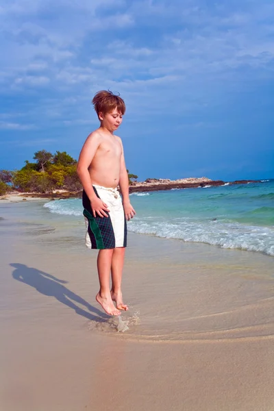 Jovem menino bonito está andando ao longo da bela praia — Fotografia de Stock