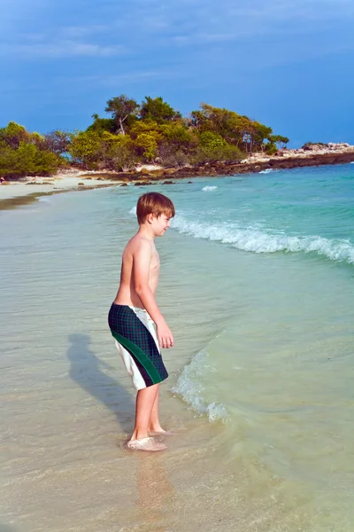 Giovane ragazzo carino sta camminando lungo la bella spiaggia — Foto Stock
