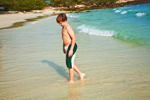 Young boy with red hair in swimsuit is running along the beautif — Stock Photo, Image