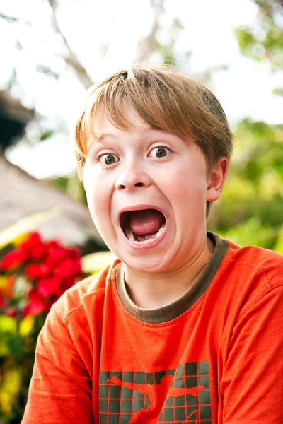 Jonge jongen zittend in een strand restaurant trekt grappige gezichten — Stockfoto