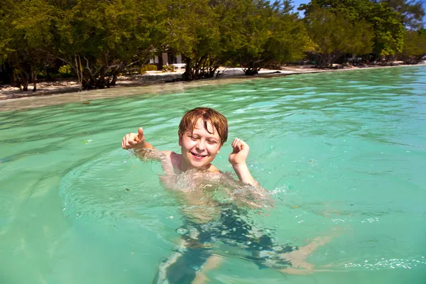 Joven chico disfruta de nadar en el mar cálido y claro y se divierte —  Fotos de Stock
