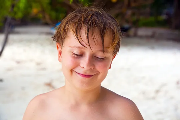 Szczęśliwy chłopiec z mokrych włosów na plaży uśmiecha się i wygląda bardzo własny — Zdjęcie stockowe