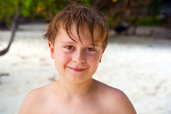 Щасливий хлопчик з мокрим волоссям на пляжі посміхається і виглядає дуже самотньо — стокове фото