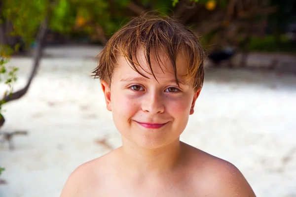 Szczęśliwy chłopiec z mokrych włosów na plaży uśmiecha się i wygląda bardzo własny — Zdjęcie stockowe