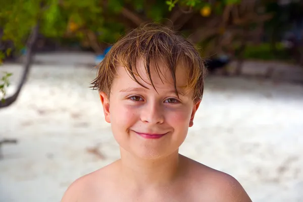 Lycklig pojke med blött hår på stranden ler och ser mycket själv — Stockfoto